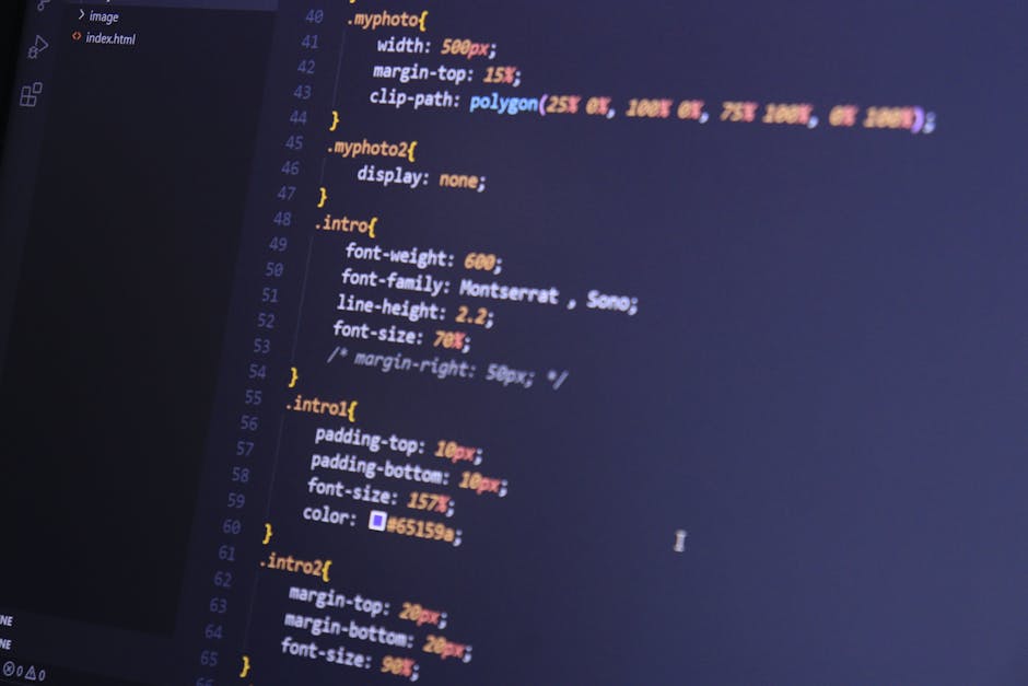 A silver laptop placed on a wooden table displaying lines of code on its screen, with a pen resting beside it. The background features a cozy, softly lit indoor space with warm-toned furniture and a m